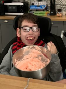 Daniel Whittingham holding a bowl of pink icing, smiling at the camera 